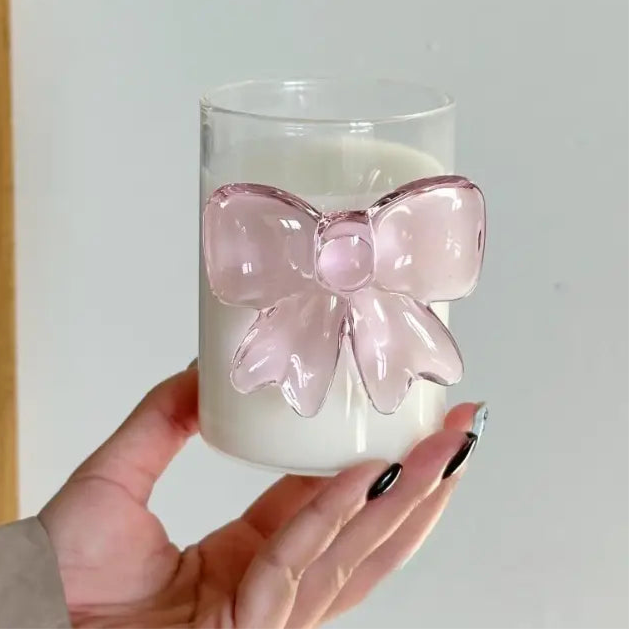 Glass candle with a pink bow held by a hand