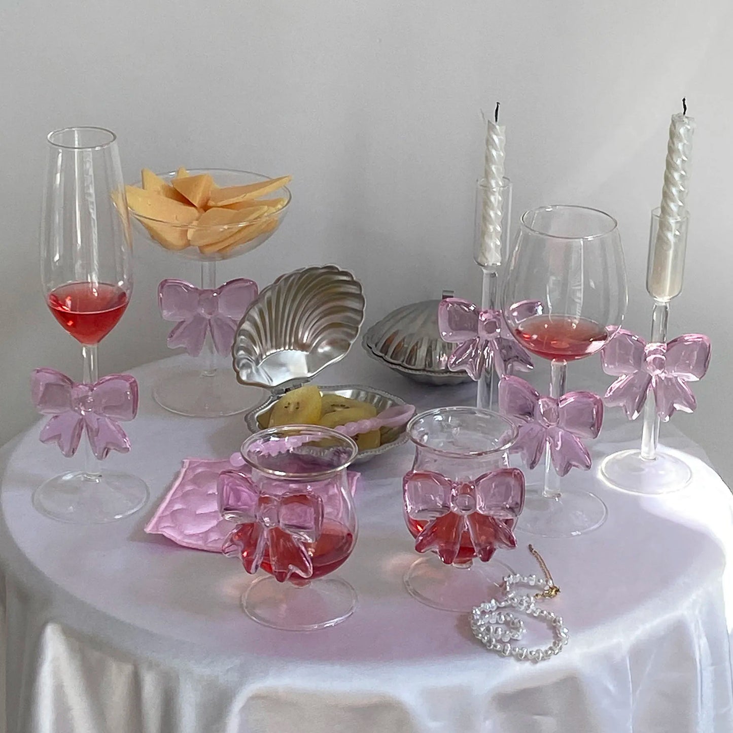 Decorative table setting with glasses, bowls, and pink bows on a white surface.