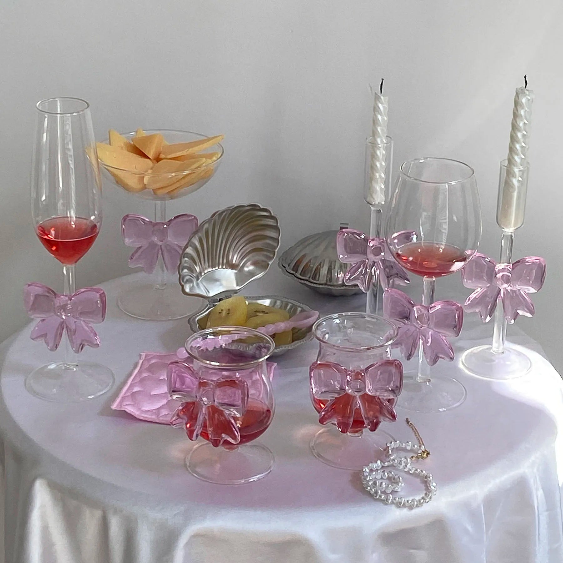 Decorative table setting with glasses, bowls, and pink bows on a white surface.