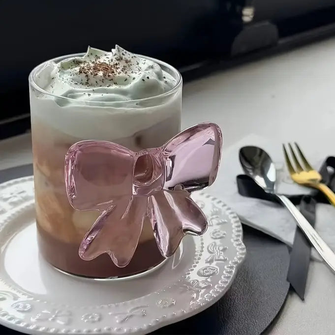 Glass with a pink bow decoration on a table with cutlery