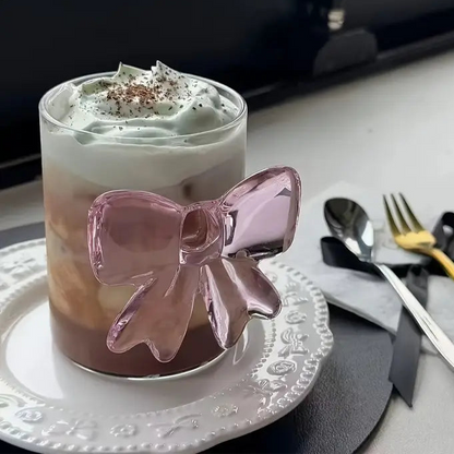 Glass with a pink bow decoration on a table with cutlery