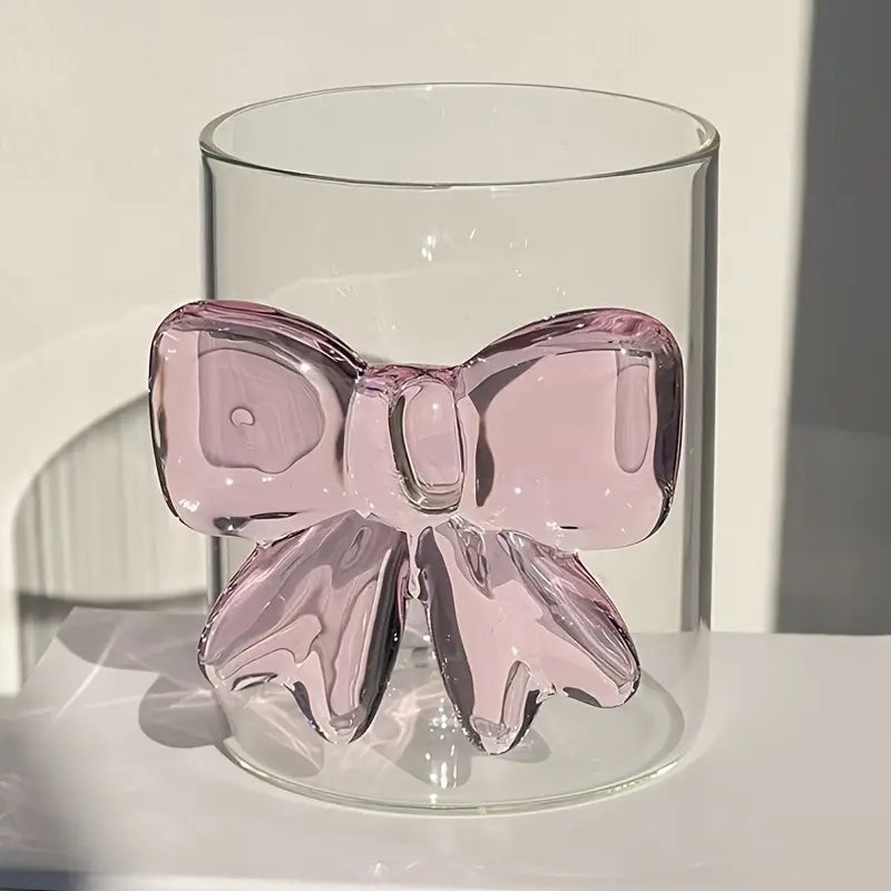 Clear glass vase with a pink bow-shaped decoration on a white background