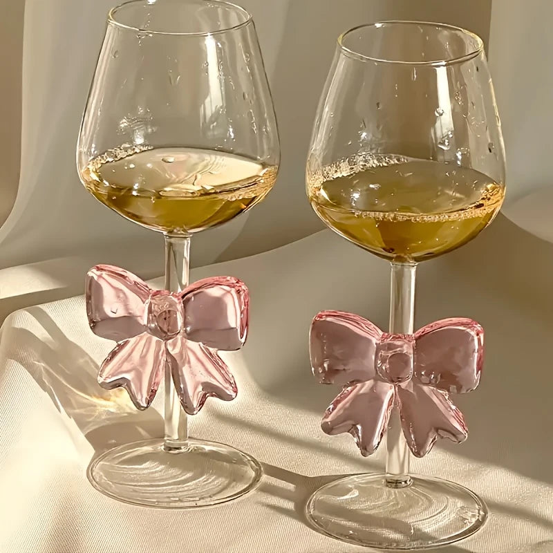 Two wine glasses with pink bow accents on a neutral background