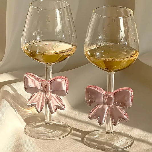 Two wine glasses with pink bow accents on a neutral background
